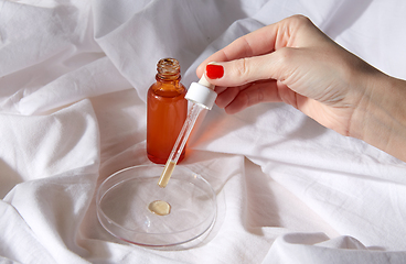 Image showing female hand with dropper applying serum to glass