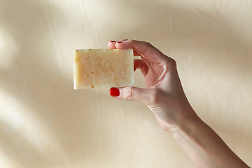 Image showing hand holding bar of craft soap on beige background