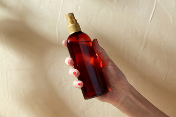 Image showing close up of hand with bottle of sunscreen oil