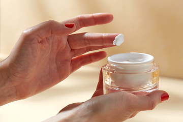 Image showing female hand holding jar of moisturizer