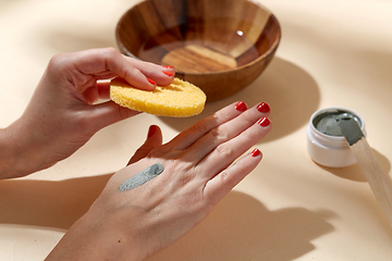 Image showing hands applying blue cosmetic clay mask to skin