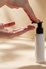 Image showing close up of hands with bottle of body lotion