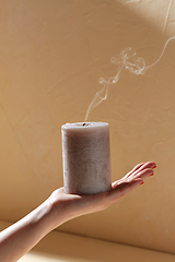 Image showing hand holding extinguished aroma candle on palm