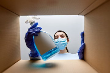 Image showing woman in mask taking cleaning supplies from box