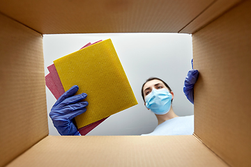 Image showing woman in mask taking cleaning supplies from box