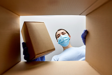 Image showing woman in mask taking box from parcel