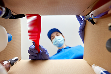 Image showing woman in mask packing parcel box with cosmetics