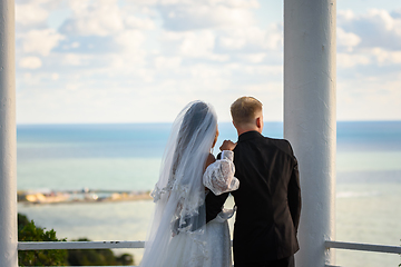 Image showing Newlyweds in a beautiful gazebo look into the distance at the sea