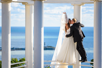 Image showing Newlyweds kiss in a beautiful gazebo standing on a metal railing