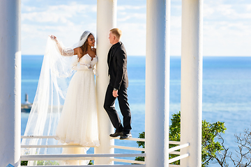 Image showing Newlyweds in a beautiful gazebo stand on a metal railing against the backdrop of the sea