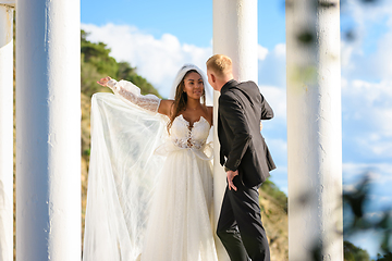 Image showing Newlyweds in a beautiful gazebo with columns against the backdrop of mountains and sky