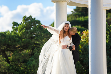 Image showing The groom kisses the neck of the bride, the bride shows her hand into the distance