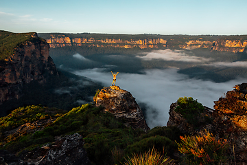 Image showing Woman hiker stands on a rocky pagoda ihigh in mountains with fog