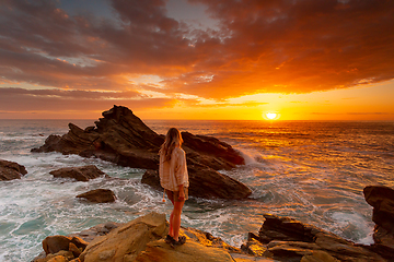 Image showing Woman watches rich red sunrise over the ocean