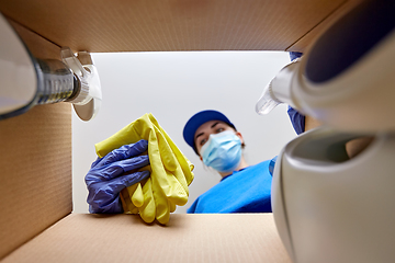 Image showing woman in mask packing cleaning supplies in box