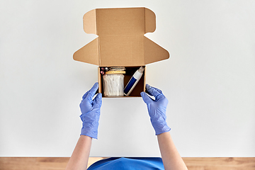 Image showing hands in gloves packing parcel box with cosmetics