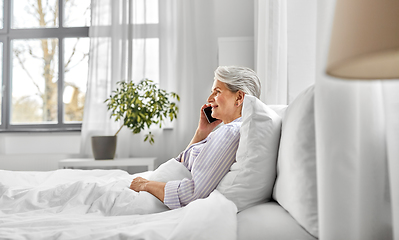 Image showing senior woman calling on smartphone in bed at home