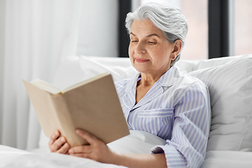 Image showing senior woman reading book in bed at home bedroom