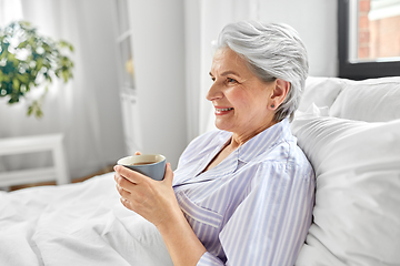 Image showing old woman with cup of coffee in bed at home