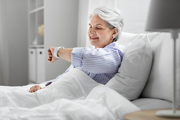 Image showing happy senior woman sitting in bed at home bedroom