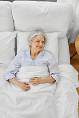 Image showing happy senior woman sleeping in bed at home bedroom