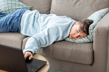 Image showing bored man with laptop lying on sofa at home