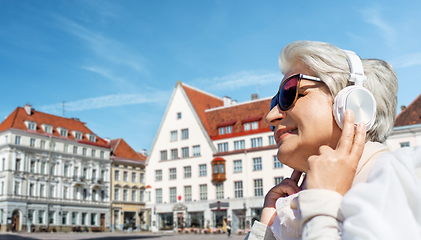 Image showing old woman in headphones listens to music outdoors