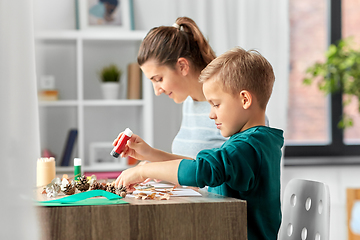 Image showing mother and son making pictures of autumn leaves