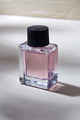 Image showing bottle of perfume on white surface with shadows