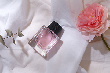 Image showing bottle of perfume and flower on white sheet