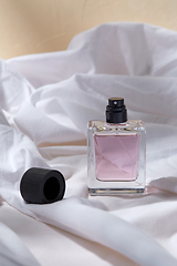 Image showing bottle of perfume and cap on white sheet