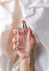 Image showing female hand with bottle of perfume on white sheet