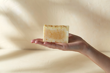 Image showing hand holding bar of craft soap on beige background