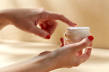 Image showing female hand holding jar of moisturizer