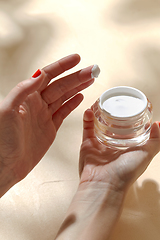 Image showing female hand holding jar of moisturizer