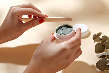 Image showing hands holding jar of blue cosmetic clay mask