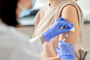 Image showing female doctor with syringe vaccinating patient