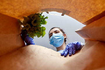 Image showing woman in gloves and mask with food in paper bag