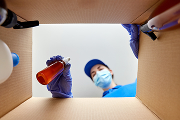 Image showing woman in mask packing parcel box with cosmetics