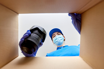 Image showing woman in mask packing camera into parcel box