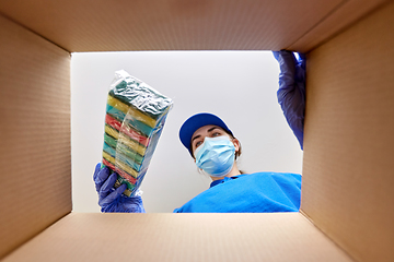 Image showing woman in mask packing kitchen sponges to box