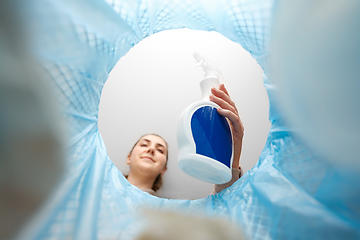 Image showing woman throwing bottle of detergent into trash can