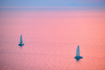 Image showing Tourist yachts boat in Aegean sea near Santorini island with tourists watching sunset viewpoint. Santorini, Greece