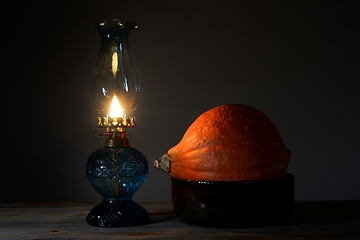 Image showing orange Hokkaido pumpkin in a ceramic bowl and a burning oil lamp