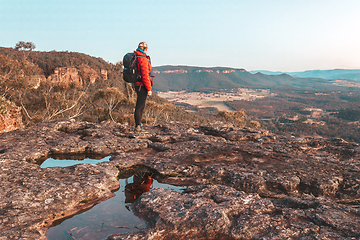 Image showing Female hiker at to the top of a rugged cliff face overlooking a