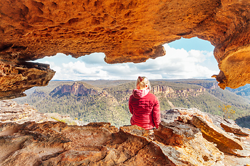 Image showing Woman sits in sandstone cave with a spectacular mountain view