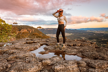 Image showing Female standing on a rock plateau as the sun sets