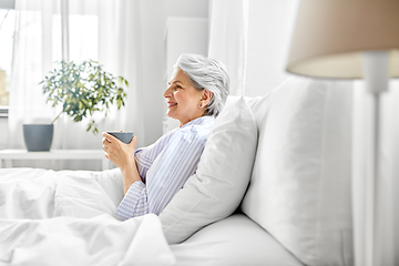 Image showing old woman with cup of coffee in bed at home