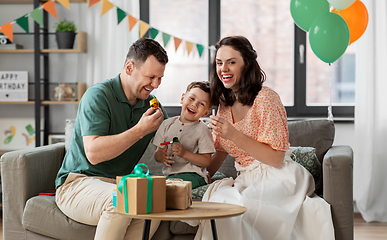 Image showing happy family with gifts and party blowers at home