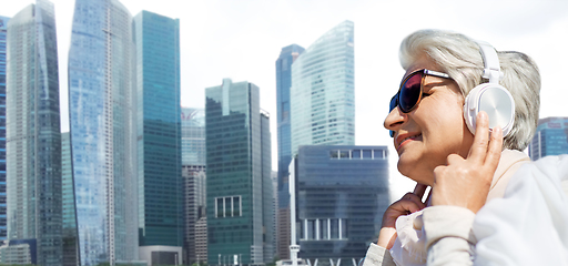 Image showing old woman in headphones listens to music in dubai